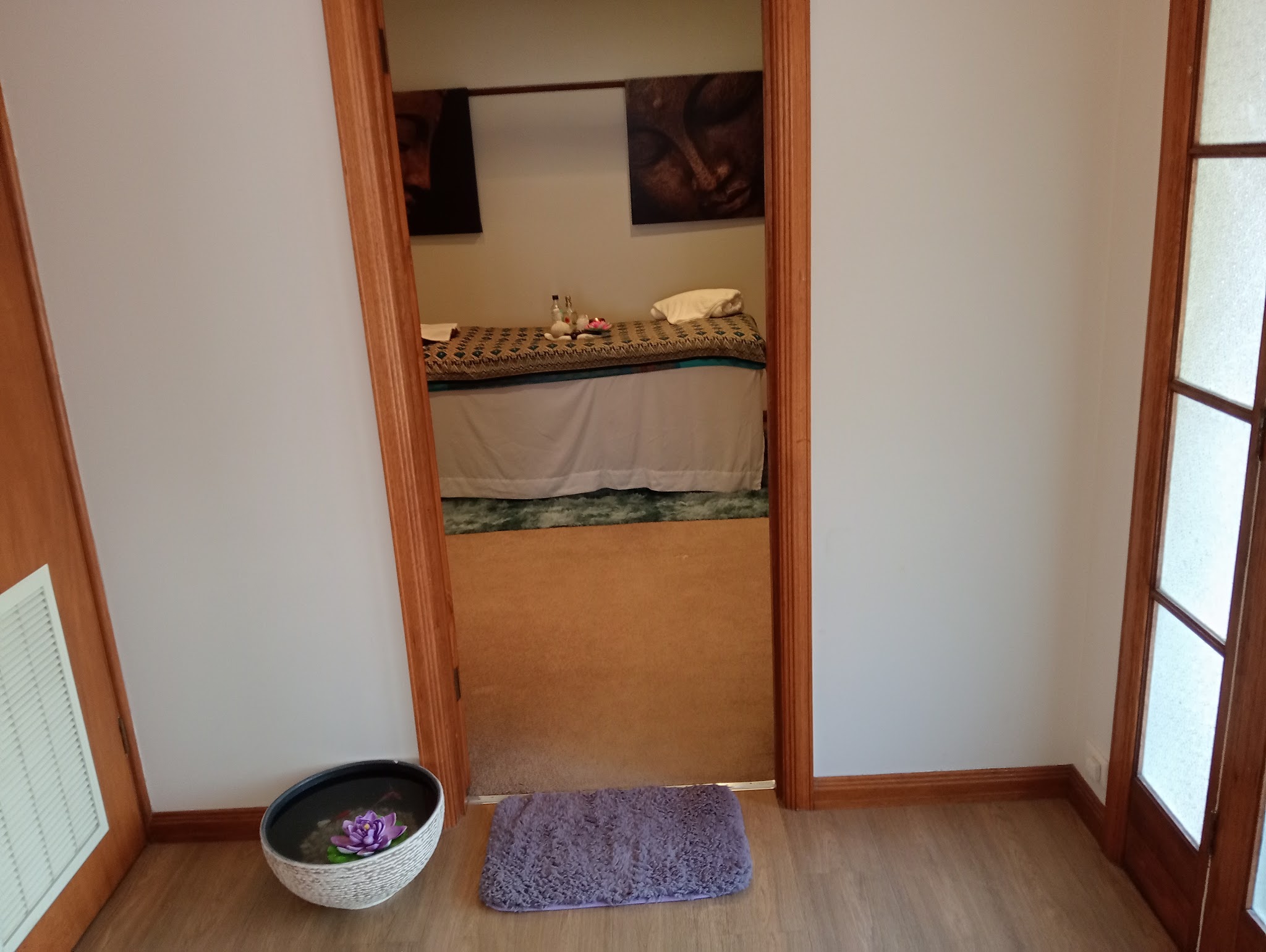 View through a timber doorway into the treatment room, with a lotus bowl on the floor outside