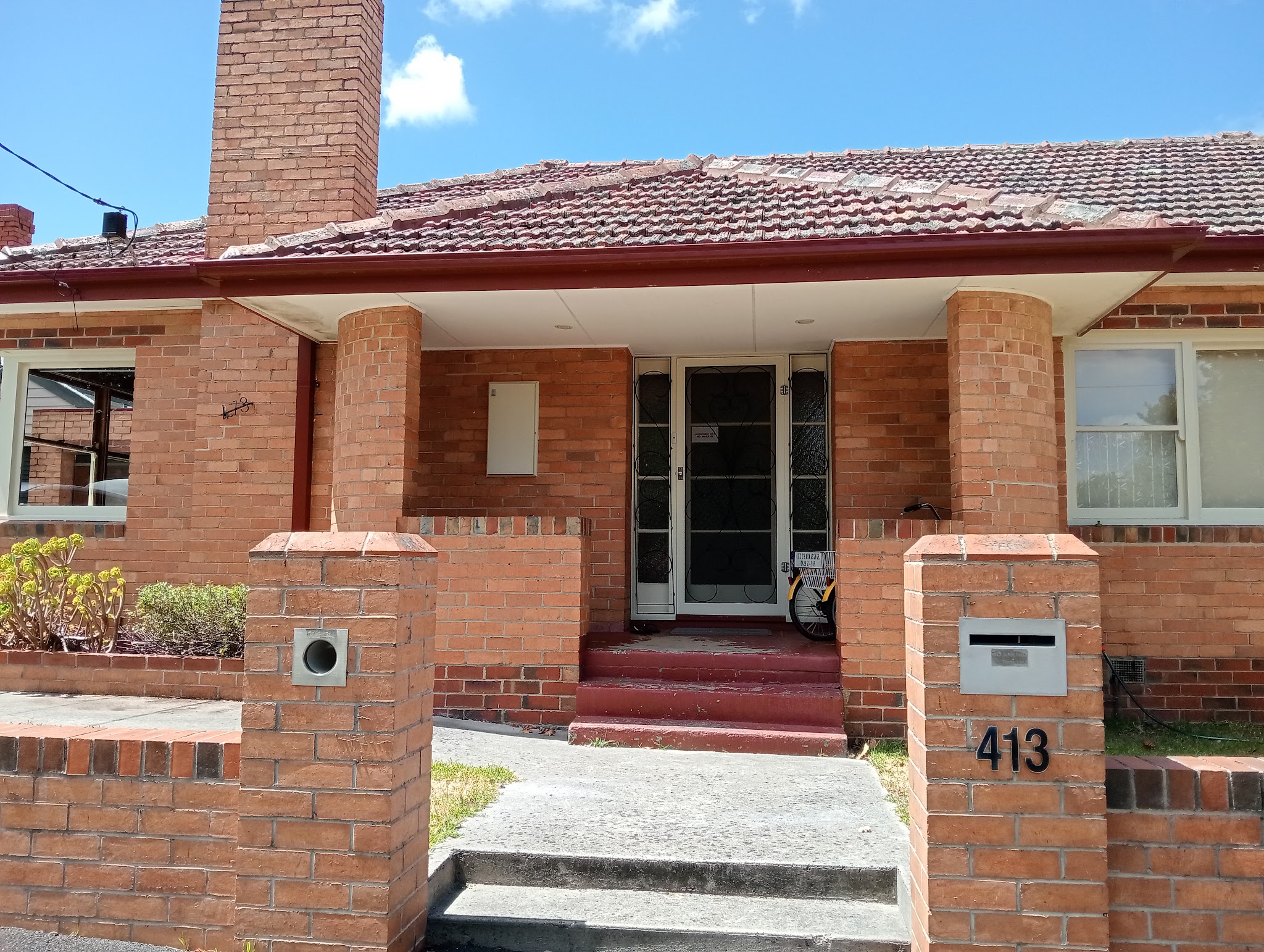 Red brick house front at 413 Dawson Street South with the number on the letterbox pillar